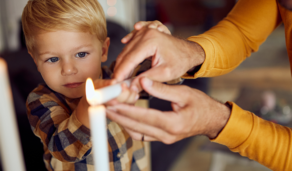 Un garçon allume une bougie avec son père