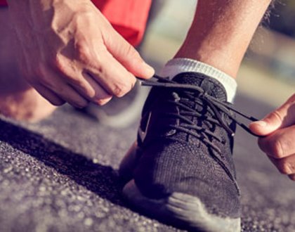 Un homme lace ses chaussures de jogging.
