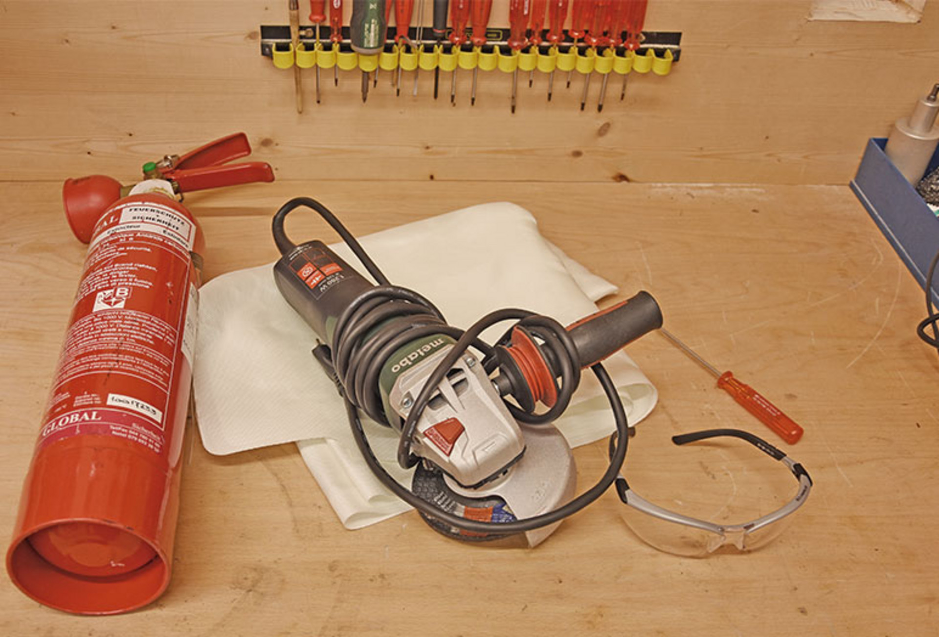 Une meuleuse d'angle et un extincteur sont posés sur une table en bois.