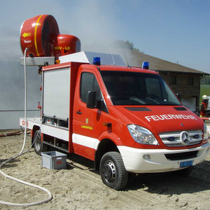 Ein Feuerwehrauto mit Gebläse steht vor einem Schweinestall