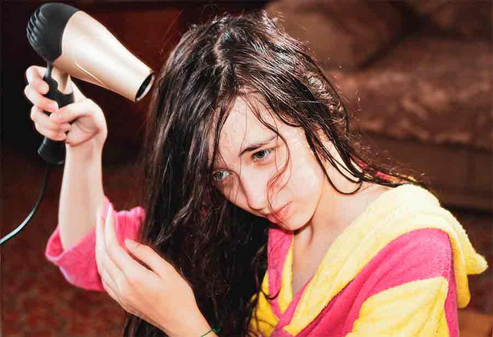 Ein Mädchen welches ihre nassen Haare fönt
