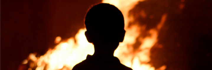 Ein Kind schaut den Flammen zu.