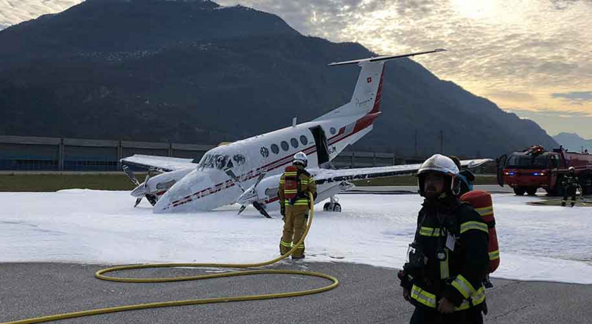 Feuerwehrleute stehen auf dem Rollfeld mit dem Flugzeug