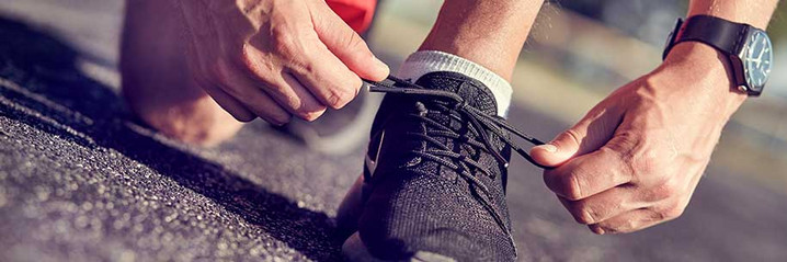 Un homme lace ses chaussures de jogging.