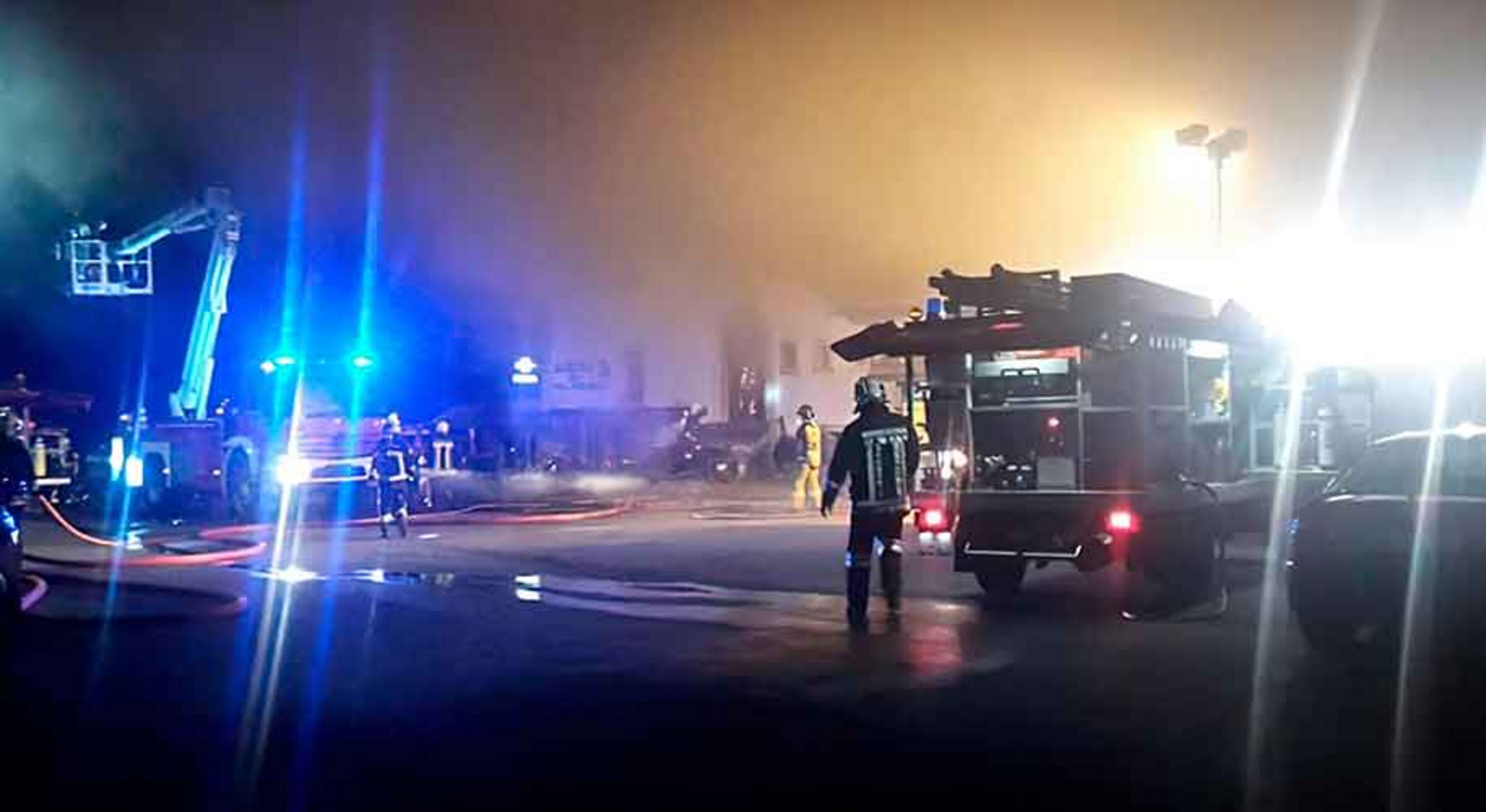 Feuerwehrfahrzeuge stehen vor einem brennenden Gebäude