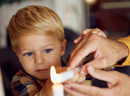 Un garçon allume une bougie avec un adulte