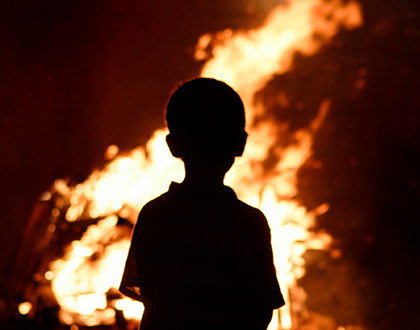 Ein Kind schaut den Flammen zu