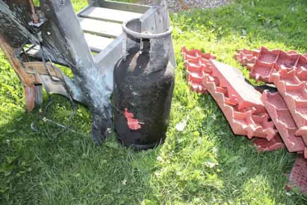 Eine verbrannte Gasflasche steht auf dem Rasen