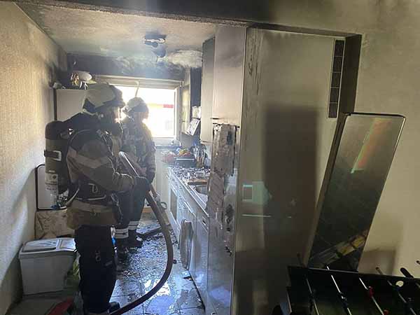Feuerwehrleute inspizieren ein ausgebranntes Zimmer