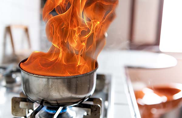 Eine Pfanne steht auf dem Kochherd und brennt. Es steigen Flammen auf.