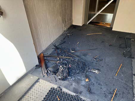 Auf dem Boden in einem Gebäude liegt ein verbranntes, nicht wiedererkennbares E-Trottinett.