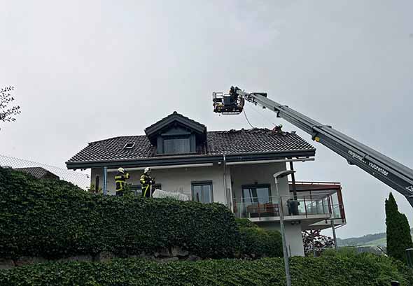 Feuerwehrleiter ragt über ausgebranntes Hausdach
