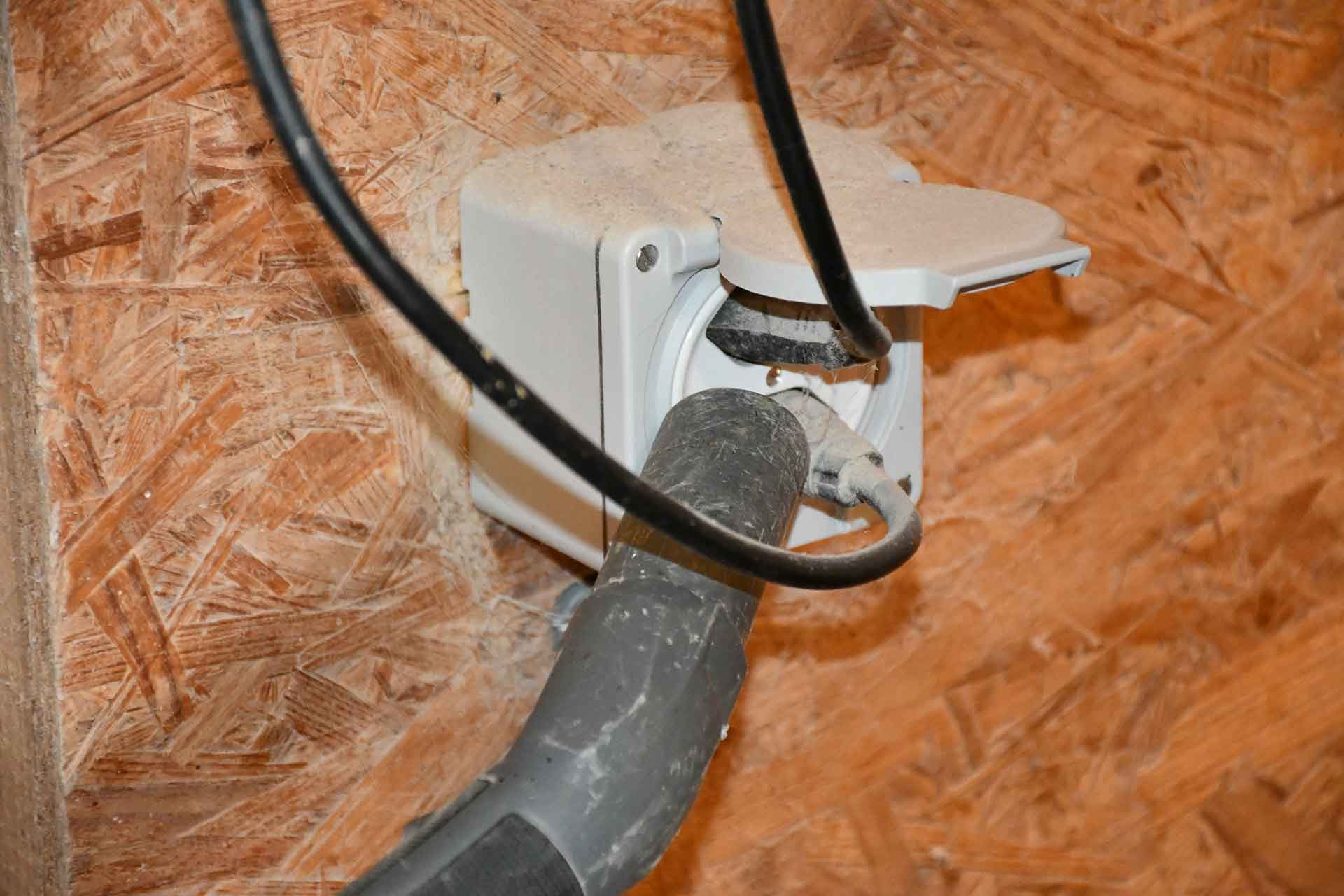 Mit einem Staubsauger wird eine Steckdose gereinigt